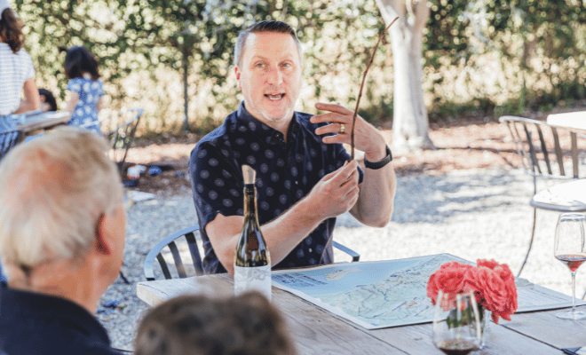 Greg Hamilton sitting at a table explaining something to guests.