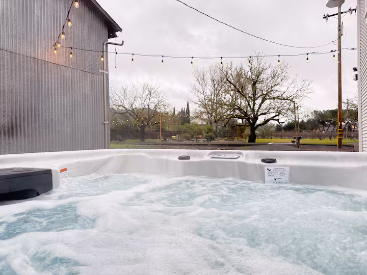 Private Carriage House hot tub running beneath outdoor string lights.