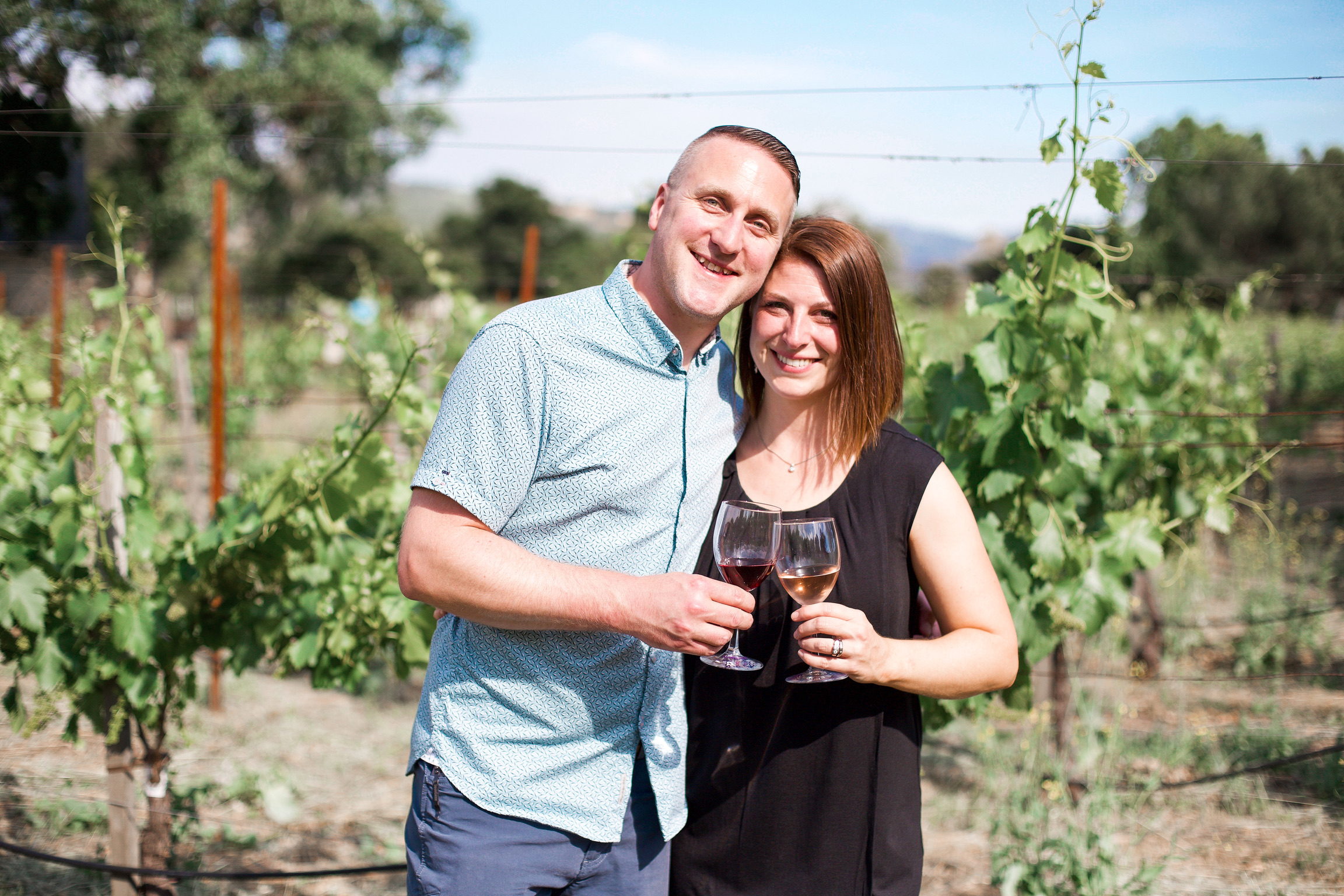 Greg and Lindsay Hamilton holding glasses of wine in their Kenwood vineyard.
